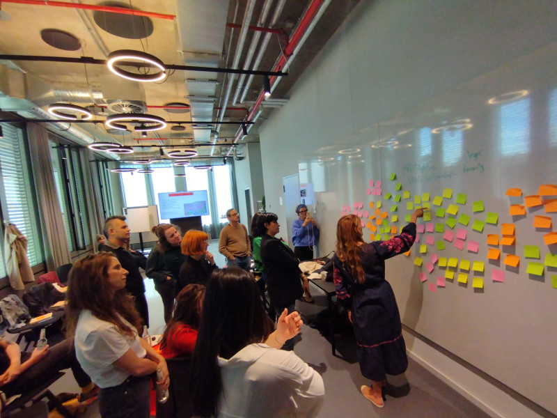 Journalists put sticky notes on a whiteboard during the Bridging News Fellowship kick-off meeting.