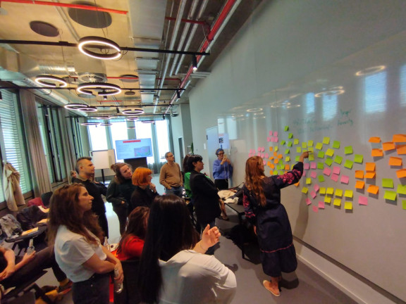 Journalists put sticky notes on a whiteboard during the Bridging News Fellowship kick-off meeting.