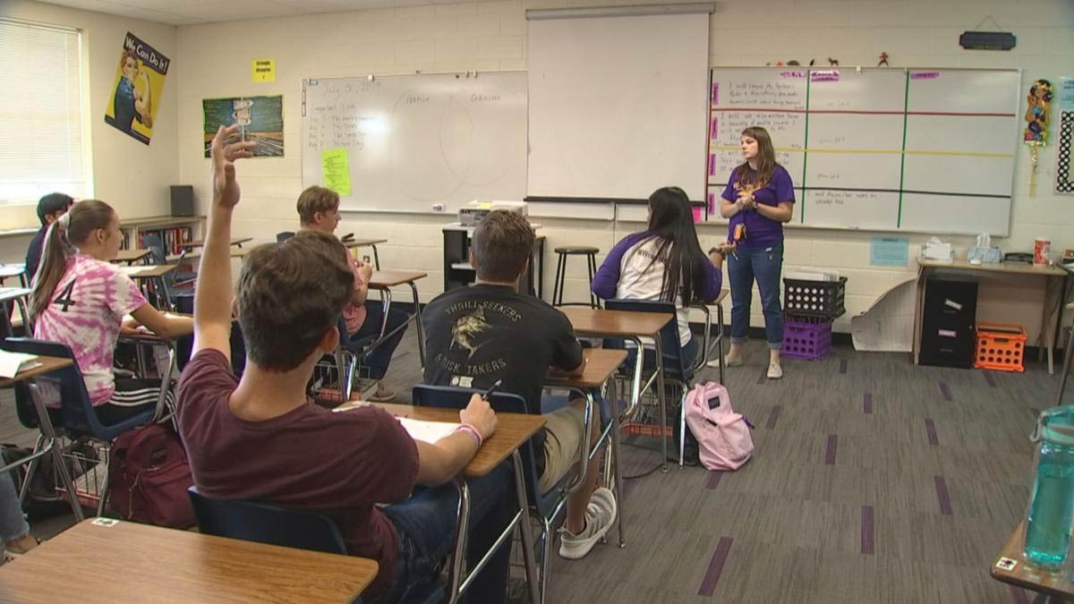 A student raising their hand in a classroom
