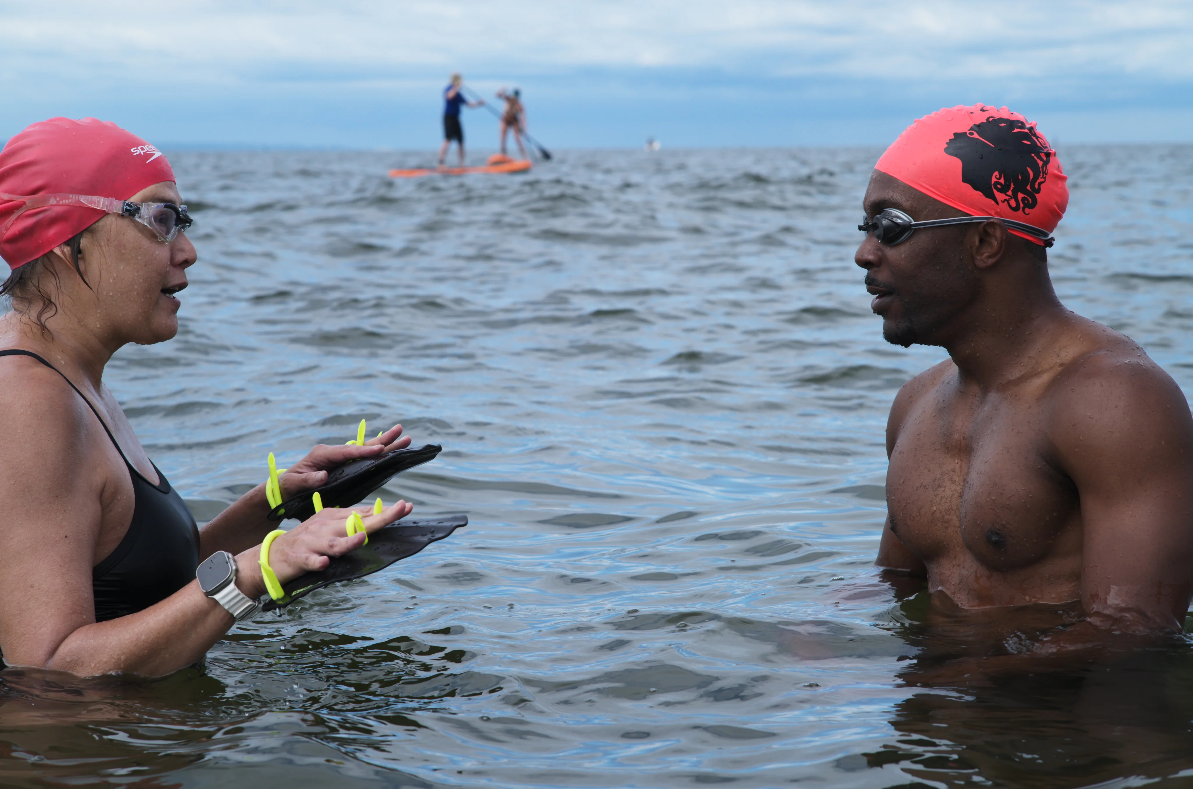 Two people have a conversation while open-water swimming