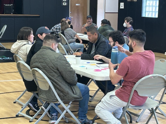 People gather around plastic tables