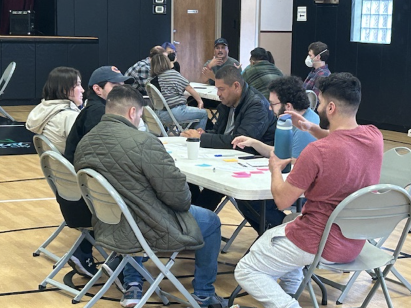 People gather around plastic tables