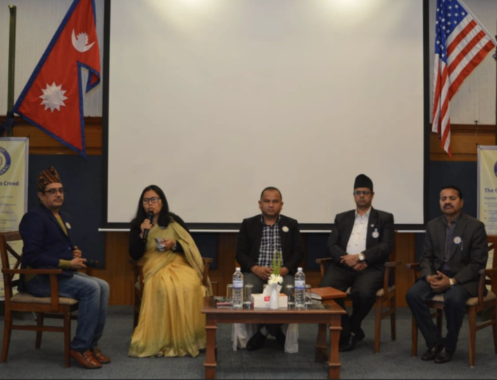 Five people are on a panel. A woman speaks into a microphone. Photo: Jhabindra Bhusal.