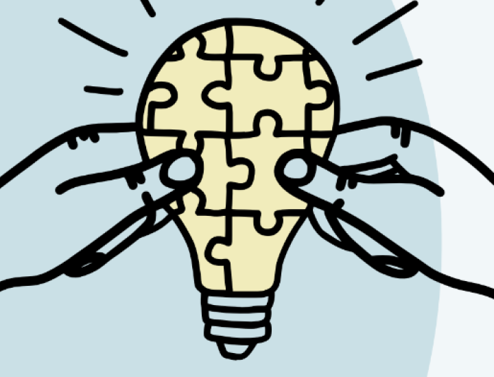 Two hands hold a lightbulb, which is covered in a puzzle piece pattern